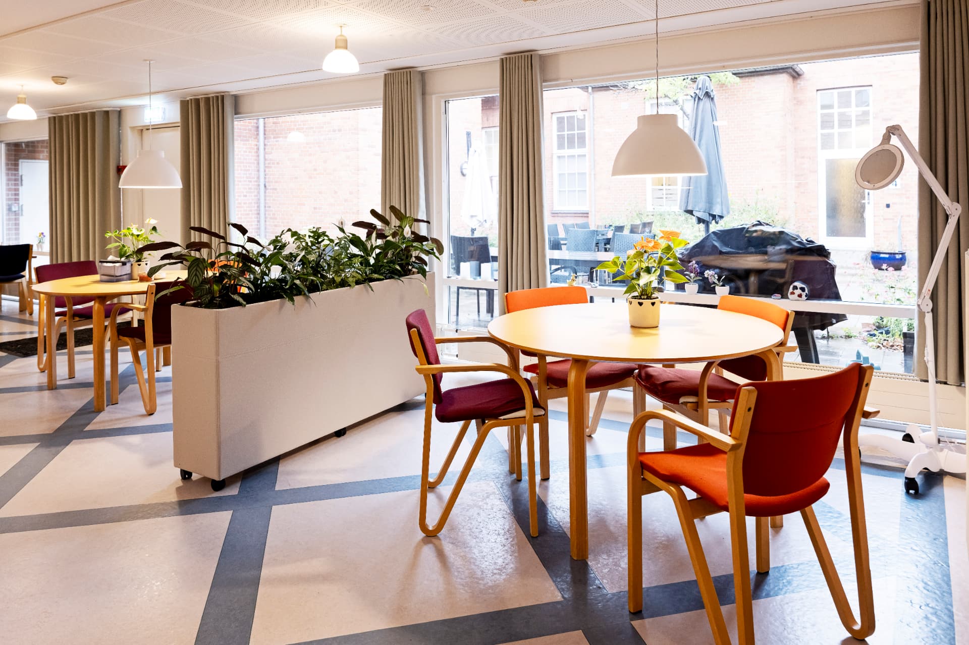Spisestuen med rolige gardiner, planter og nye lamper efter ændringen